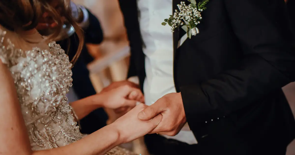 Primer plano de las manos de una pareja tomadas de la mano en una ceremonia laica al aire libre